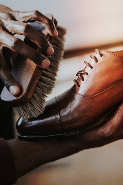 Чоловік наносить лак для взуття на своє коричневе шкіряне взуття
 - Фото, зображення
