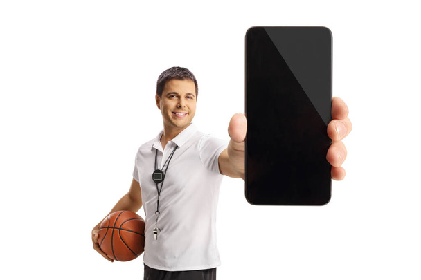 Basketball coach holding a ball and showing a smartphone isolated on white background - Zdjęcie, obraz