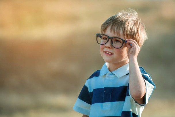 4 yaşında, gözlüklü şirin bir çocuğun açık hava portresi. Akıllı küçük çocuk ilkokula geri dön. Anaokulu çocukları eğitime hazır. - Fotoğraf, Görsel
