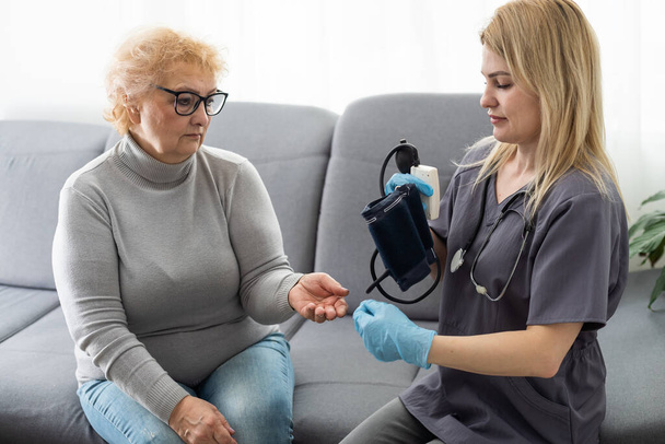 Glückliche Patientin hält Pflegerin an der Hand, während sie Zeit miteinander verbringt - Foto, Bild