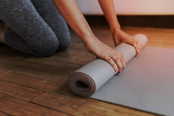 Sporty woman rolling a yoga mat - Foto, imagen