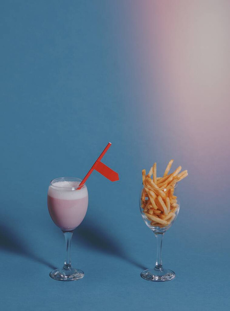 French fries in a wine glass beside a pink drink - Photo, Image