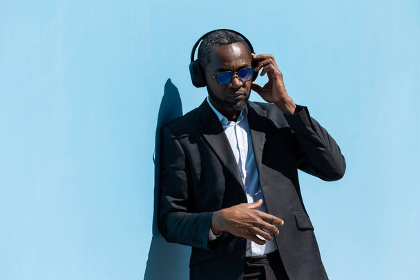 Elegant man. Mature dark-skinned man in a suit and sunglasses standing near the wall - Photo, image