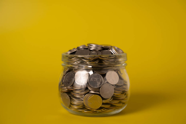 Coins in glass jar on abstract background, Financial business investment, Growing money, Global financial crisis, People saving money, Money saving concept. High quality photo - Foto, Imagen