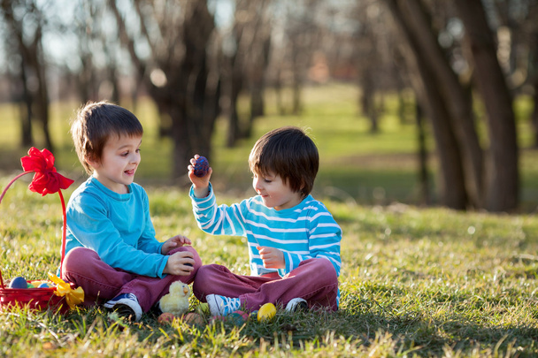 Two boys in the park, having fun with colored eggs for Easter - Photo, image