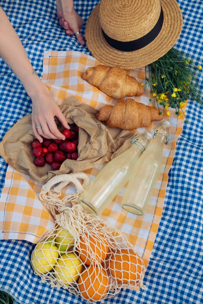 Enjoying picnic: croissants, strawberries, lemonade on checkered blanket - Zdjęcie, obraz