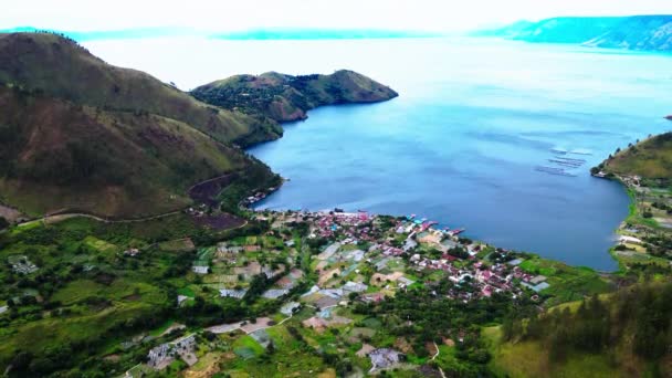 Awe-Inspiring Aerial Footage Toont een schilderachtig dorp grenzend aan een adembenemend groot meer, omlijst door Rolling Hills - Video