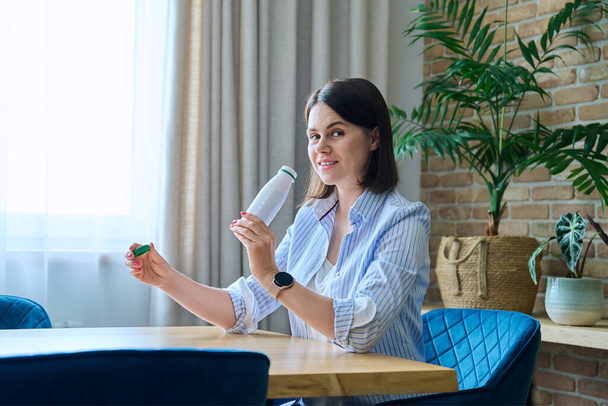 Young woman drinking fermented milk product from bottle, sitting at table at home, healthy breakfast. Dairy vitamin products, yogurt, kefir, diet, healthy eating concept - Foto, Bild
