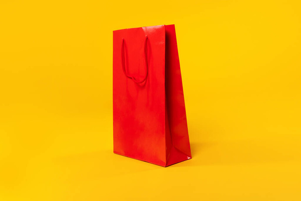 Fashion concept. Big red shopping bag with empty space for your text or design, yellow studio background, mockup, collage. Season sales, promo, offer, black friday concept - 写真・画像