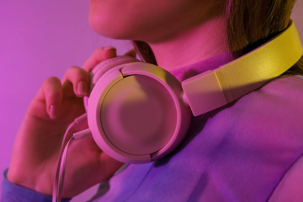 Junge Frau mit Kopfhörer hört Musik auf farbigem Hintergrund - Foto, Bild