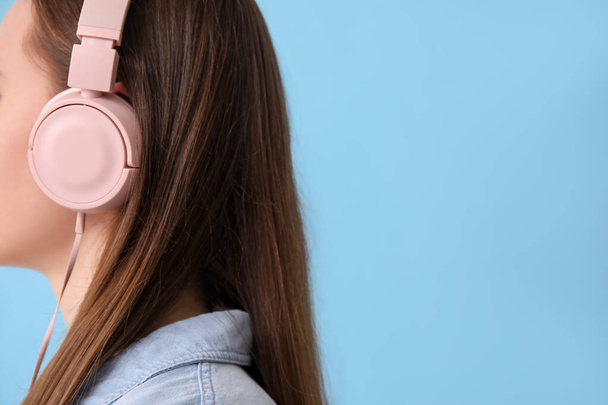 Young woman in headphones listening to music on blue background - Фото, изображение