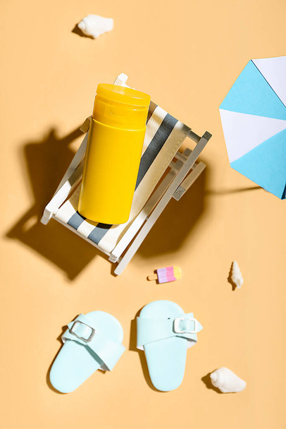 Renkli arka planda minyatür şezlonga, şemsiyeye ve güneş kremine sahip yaratıcı kompozisyon - Fotoğraf, Görsel