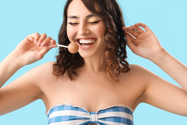 Young woman with lollipop on blue background, closeup - Photo, Image