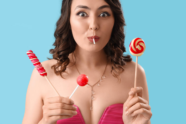Young woman with lollipops on blue background, closeup - Foto, immagini