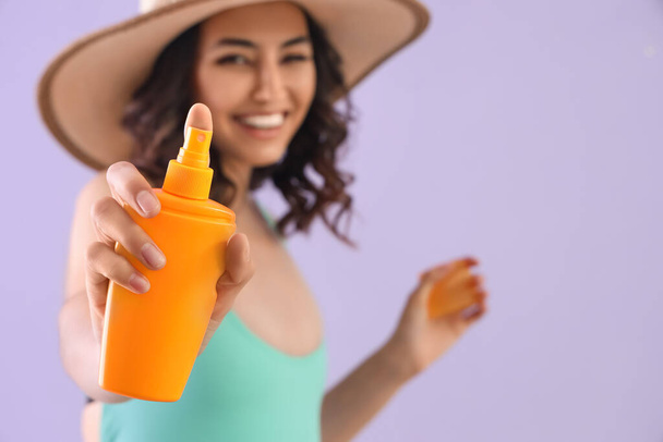 Young woman with sunscreen cream on lilac background, closeup - Photo, image