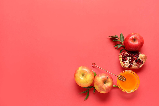 Jar of honey, pomegranate and apples for Rosh Hashanah celebration (Jewish New Year) on red background - Photo, Image