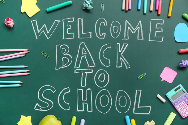 Different stationery with text WELCOME BACK TO SCHOOL on green chalkboard - Photo, Image
