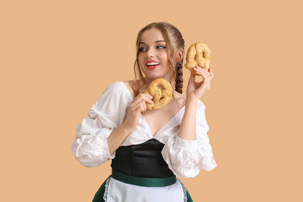 Hermosa camarera Octoberfest con pretzels sobre fondo beige - Foto, Imagen