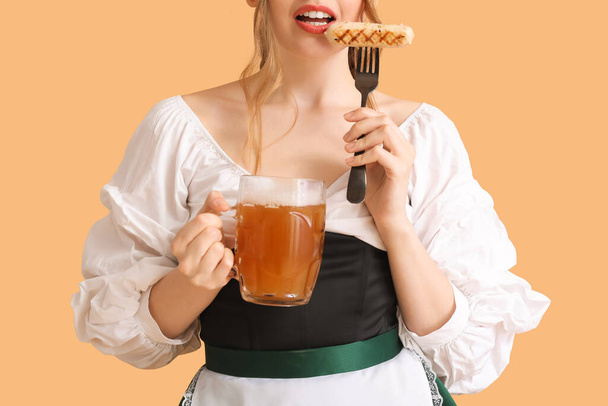 Beautiful Octoberfest waitress with beer and sausage on beige background, closeup - Zdjęcie, obraz