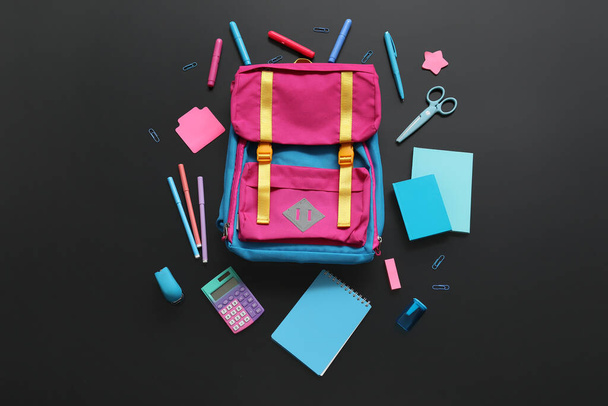 Colorful school backpack with different stationery on black background - Photo, Image