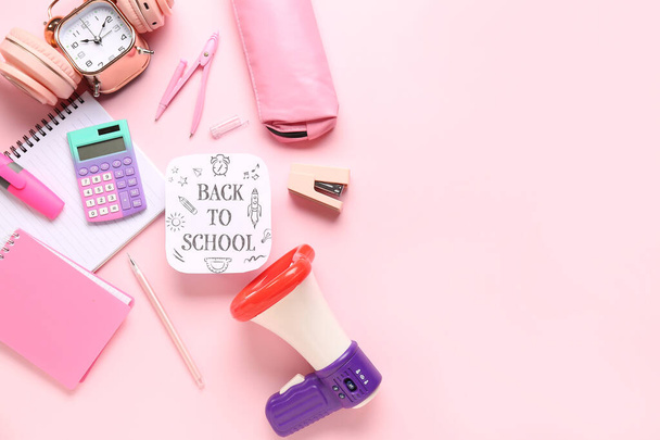 Headphones, alarm clock, megaphone and sheet with text BACK TO SCHOOL on pink background - Photo, Image