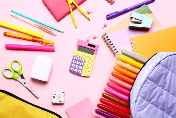 Rugzak met rekenmachine en verschillende briefpapier op roze achtergrond - Foto, afbeelding
