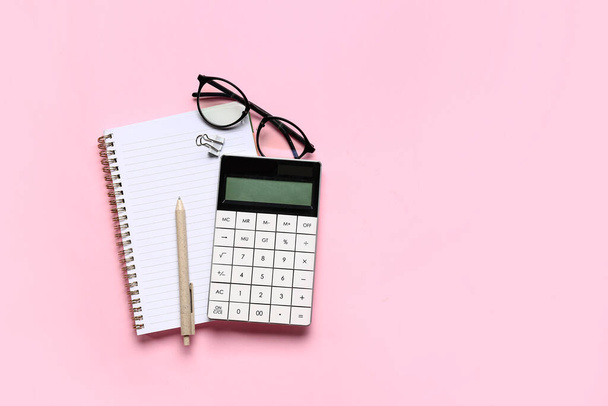 Calculadora moderna con anteojos y papelería sobre fondo rosa - Foto, Imagen