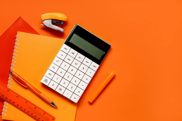 Modern calculator with stationery on orange background - Photo, image