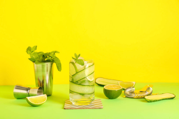 Glass of cucumber mojito with bartender tools on color background - 写真・画像