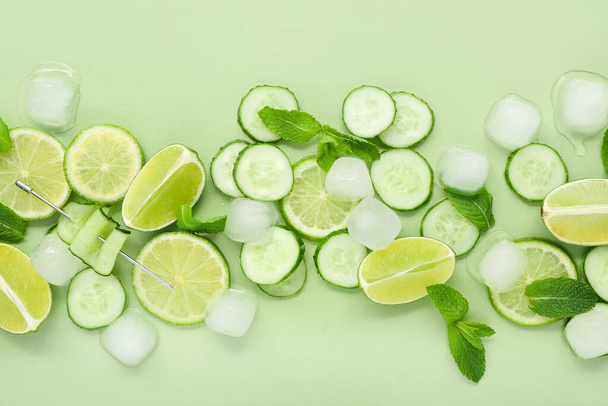 Świeża limonka z ogórkiem, miętą i kostkami lodu na zielonym tle. Składniki mojito - Zdjęcie, obraz