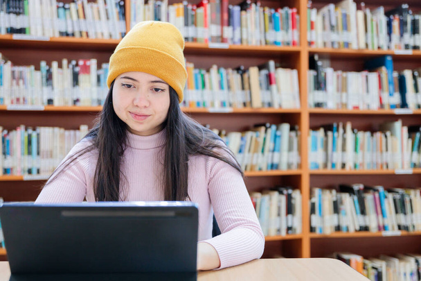 Akadémiai Üldözők: Fiatal Női Egyetemi Hallgató Tanulmányait tabletjével a könyvtárban. Kiváló minőségű fénykép - Fotó, kép