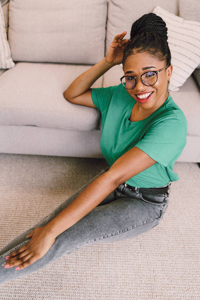 Portrait of attractive black woman smiling and happy on light gray background, African American woman wearing green top - Photo, Image