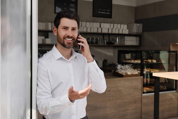 Happy business owner talking on phone in bakery shop. Space for text - Valokuva, kuva