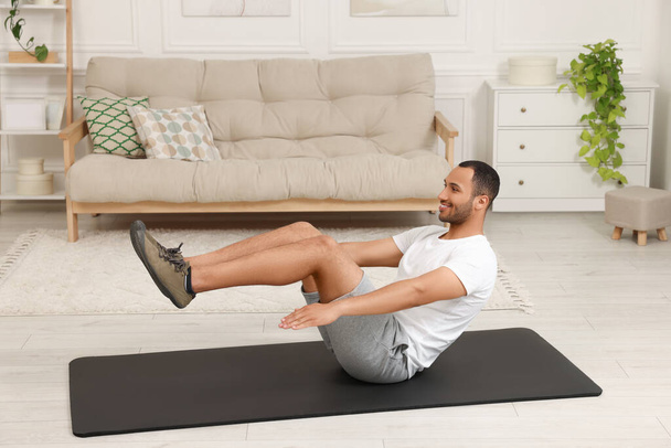 Man doing morning exercise on fitness mat at home - Foto, Bild