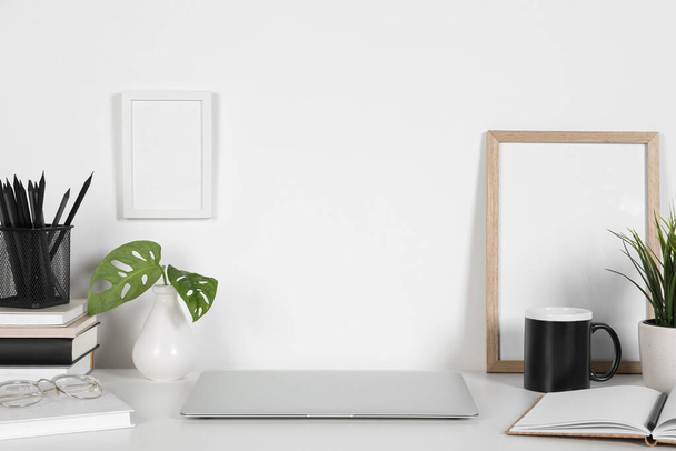 Cozy workspace with laptop, houseplants and stationery on white desk at home - Zdjęcie, obraz