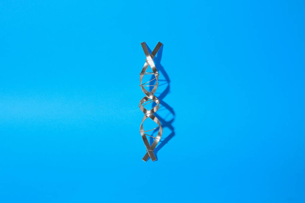 DNA molecular chain model made of metal on blue background, top view - Фото, изображение