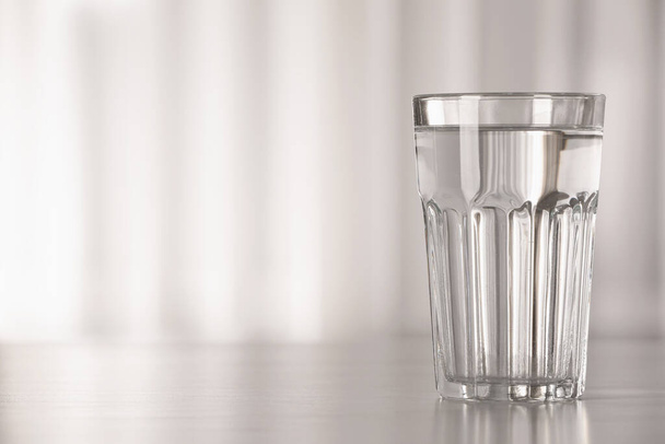 Glass with water on table against blurred background. Space for text - Фото, зображення