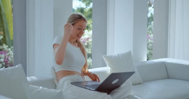 Onnellinen järkyttynyt valkoihoinen nainen katselee kannettavan tietokoneen näytön istuu sohvalla kotona. Nainen katselee kannettavaa tietokonetta yllättynyt saada hyviä tuloksia juhlia internet tarjous voittaa palkinnon, osoittaa kyllä voitto ele - Materiaali, video