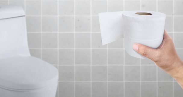 A person suffering from diarrhea holds a roll of toilet paper in front of the toilet bowl - Foto, Imagem