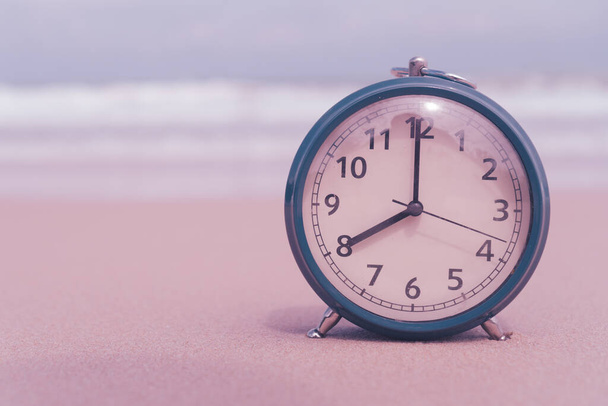 Clock set 8 am in morning on sand and beach background. - Фото, изображение