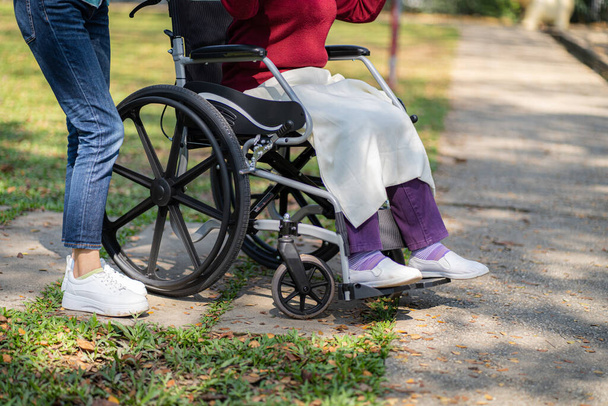 Nursing home. Young caregiver helping senior woman in wheelchair - Fotó, kép