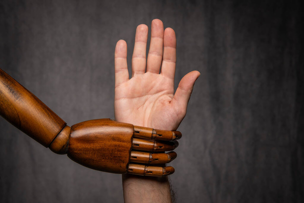 Acercamiento de la mano del estilo retro del maniquí de los modistas de madera que sostiene la mano humana - Foto, imagen