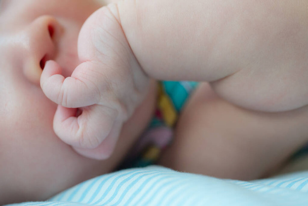 Kuva vangitsee söpön hetken vastasyntyneestä vauvasta, joka yrittää tutkia laittamalla sormen nenäänsä, esittelemällä uteliaisuuttaan ja varhaista motoristen taitojen kehitystä. - Valokuva, kuva