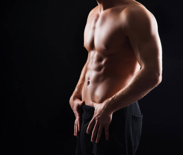 Strong, fit and sporty bodybuilder man over black background. Sport and fitness concept - Fotografie, Obrázek