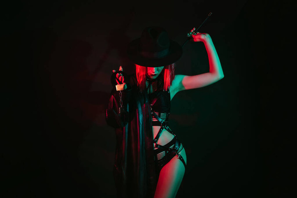sexy mujer en hermosa ropa interior en un sombrero sosteniendo un látigo de cuero flogger y esposas para BDSM sexo con sumisión y dominación - Foto, imagen