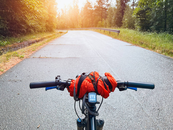 Bike summer ride. First-Person View of a Cyclist Embracing the Outdoors. holding bike handlebar with one hand. summertime outdoor leisure sport activity. first-person view bicycle riding - Photo, Image