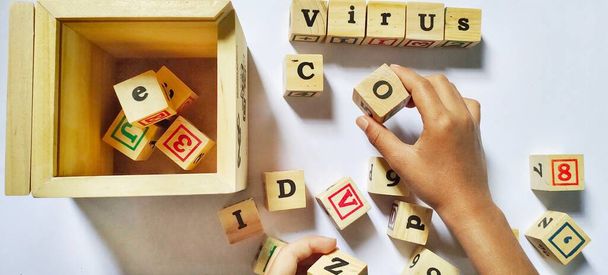 Little boy playing toy wooden cubes arrange the word "corona virus" - 写真・画像