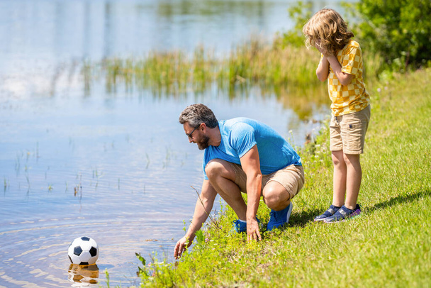 son has bonding time with father outdoor. favorite activity. Father and son enjoy a friendly game of football. happy childhood of son playing with father. father and son summer activity. - Valokuva, kuva