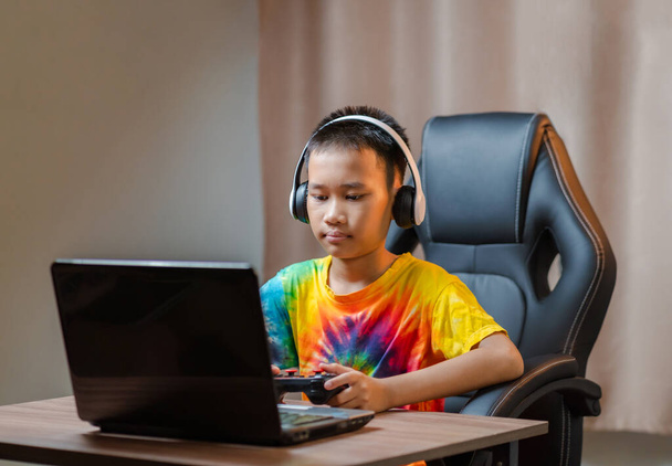 Asian boy playing competitive games online at home at home during his free time. via joystick - Φωτογραφία, εικόνα