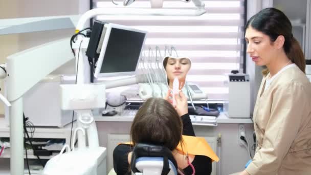Konzultace se zubařem a pacientem. Pacient se podívá do zubního zrcátka na výsledek stomatologické léčby. Spokojen zákazník - Záběry, video